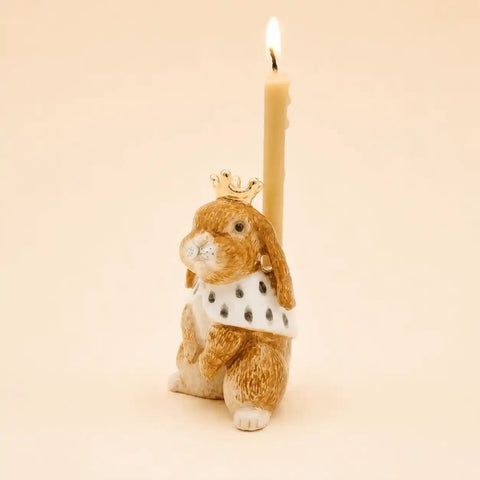 A decorative rabbit-shaped candle holder with a lit cream candle inserted behind it. 