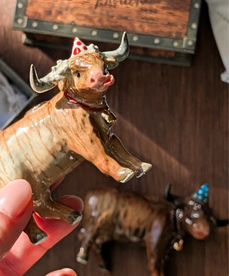 Hand-painted Highland cow cake topper wearing a red party hat